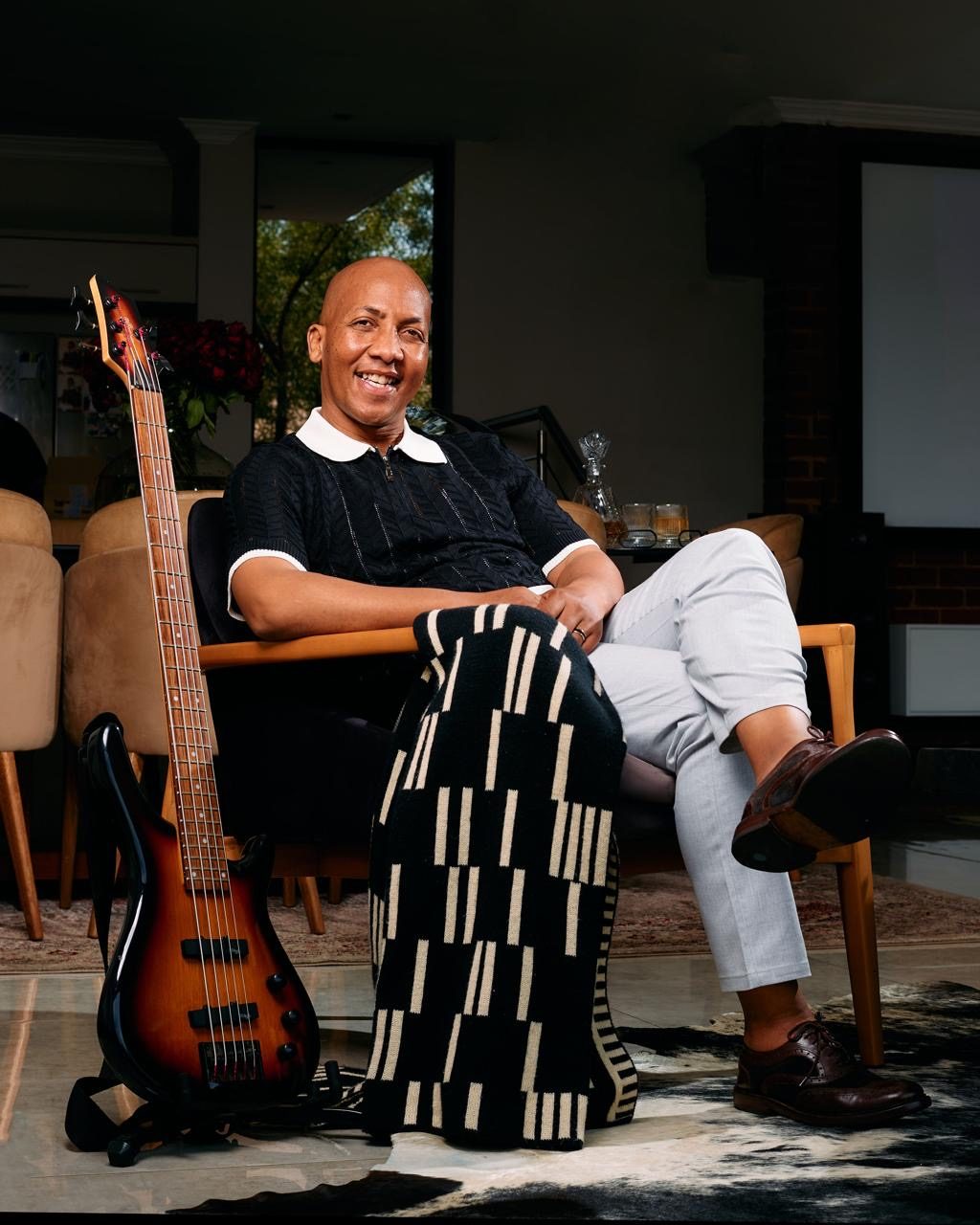 C’ya seated beside his bass guitar